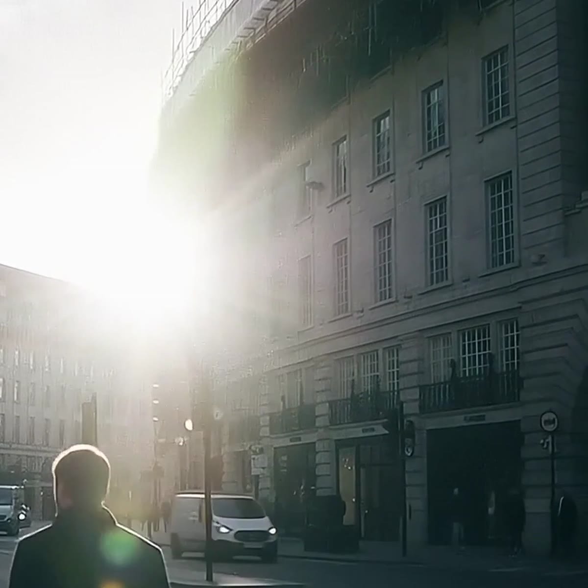Person walking at a steady pace on a sunny city street