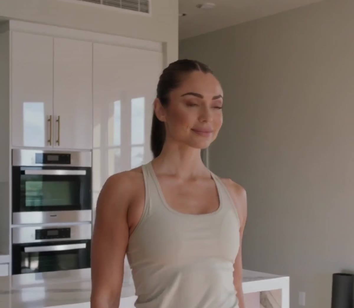 Woman standing in her kitchen before measuring her waist at the belly button
